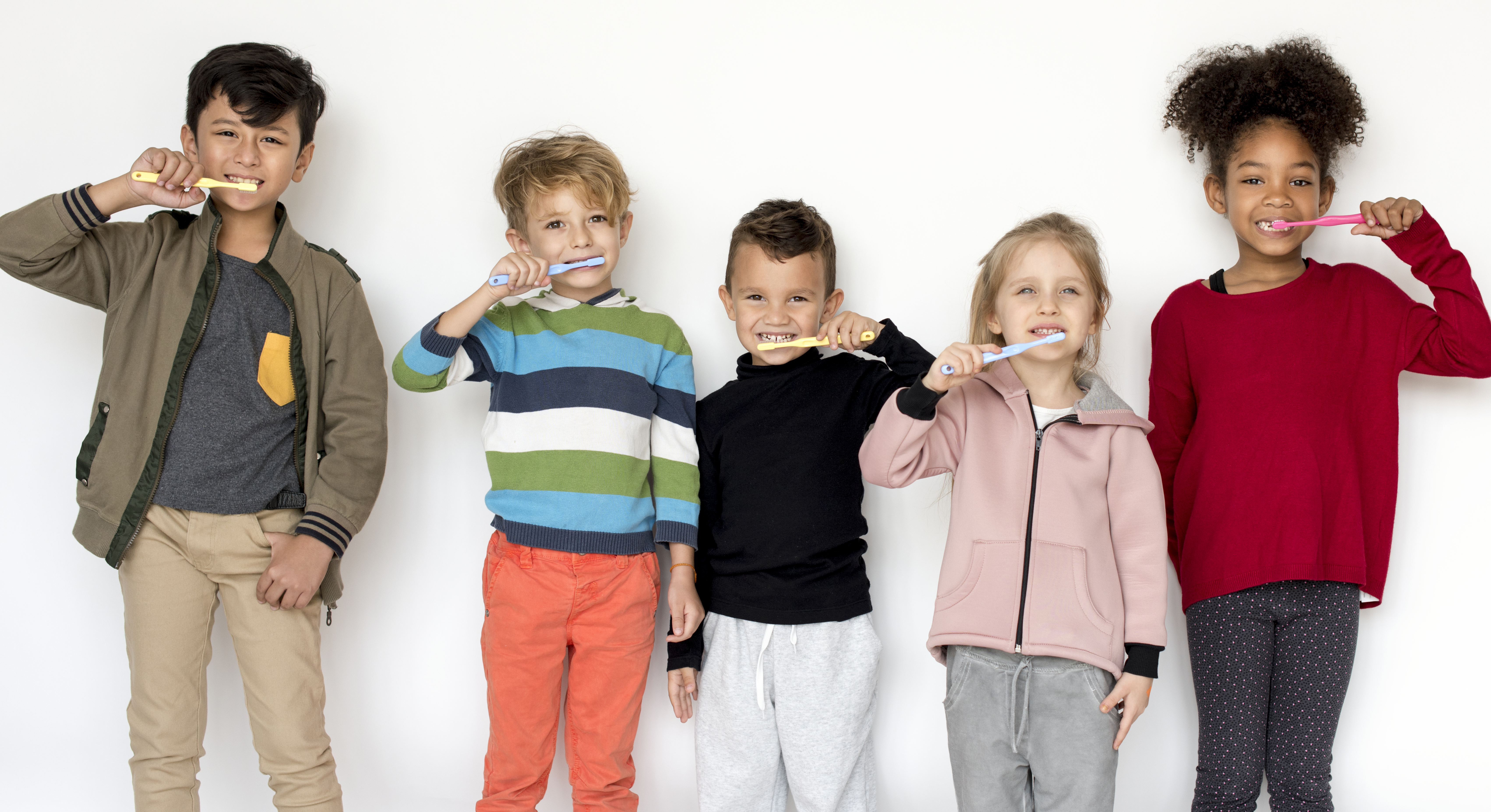 children standing holding a tooth brush brushing their teeth